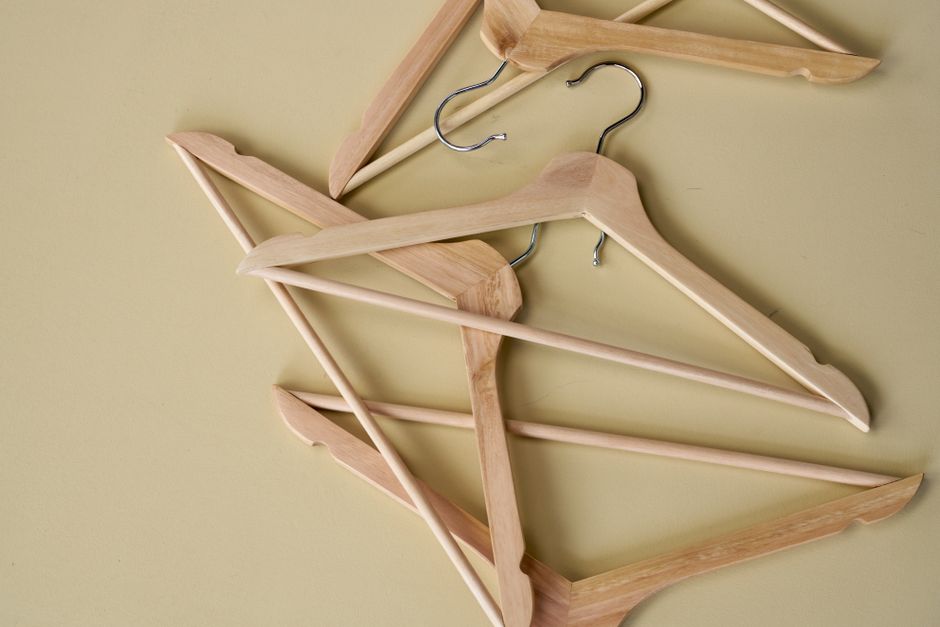 Top view of wooden clothes hangers arranged on a yellow background for minimalist decor.