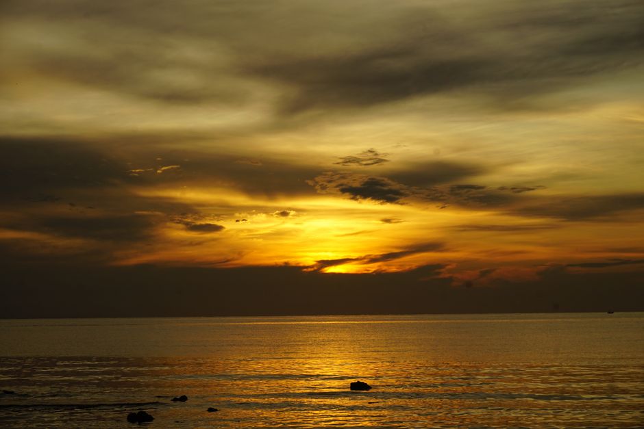 A breathtaking view of the ocean at sunset with vibrant golden hues reflecting off the water.