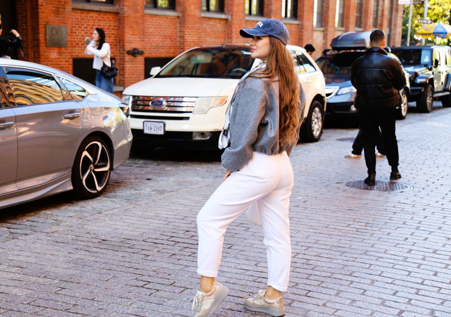 Fashionable woman posing confidently on a cobblestone street in New York City.