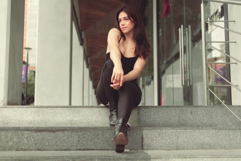 Relaxed young woman in casual attire sitting on outdoor steps.