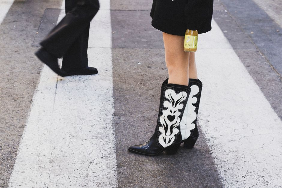 Fashionable cowboy boots on a city crosswalk in Valencia, Spain, showcasing urban style.