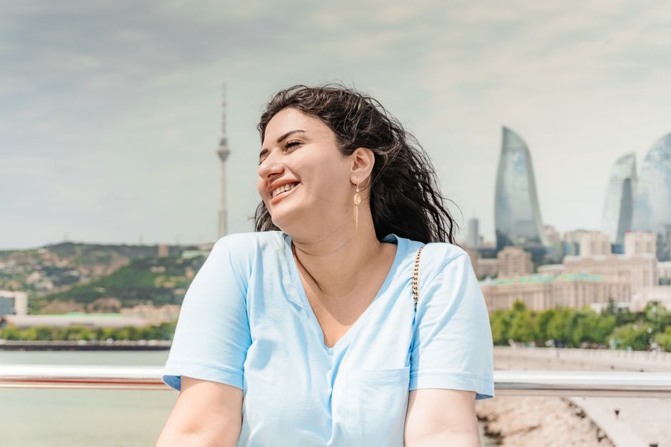 Woman smiling with Baku's Flame Towers in the background, evoking a sense of joy.