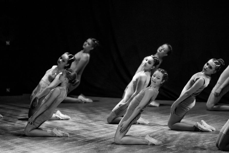 Captivating black and white photo of young ballet dancers performing on a dimly lit stage.
