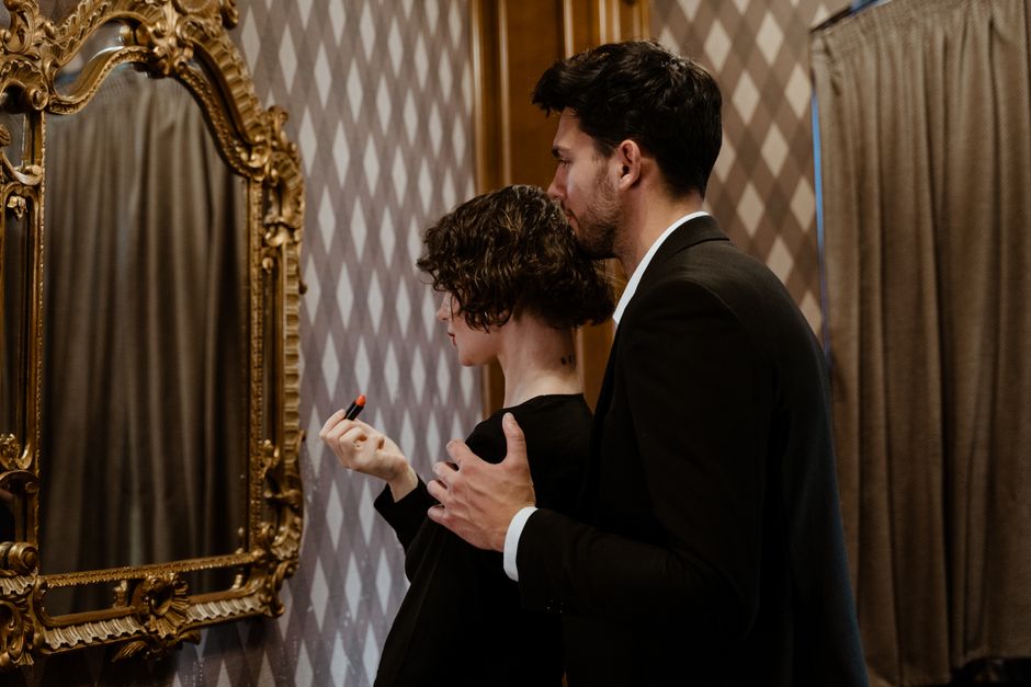 A romantic moment of a couple embracing while getting ready, reflected in a vintage mirror.