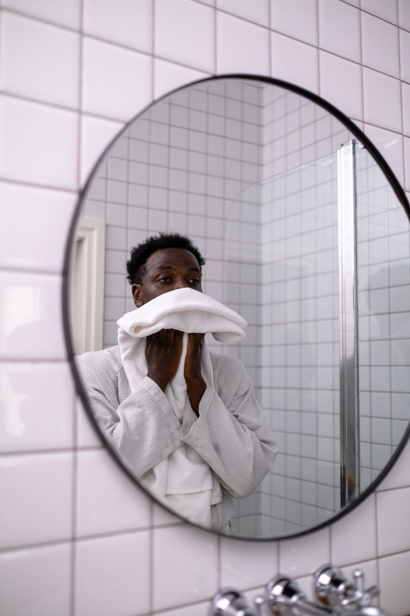 Man in a white robe during a quiet bathroom grooming routine