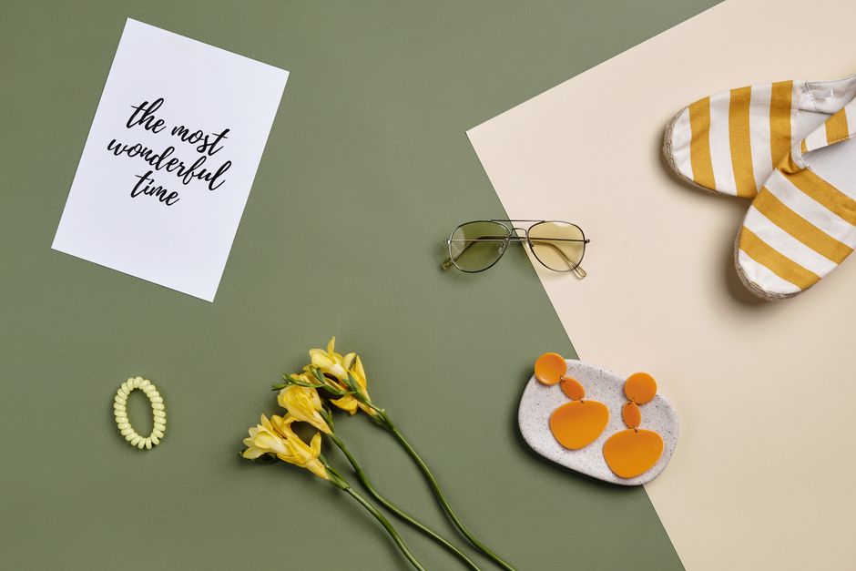 Flat lay of summer accessories including sunglasses, flowers, and a card.