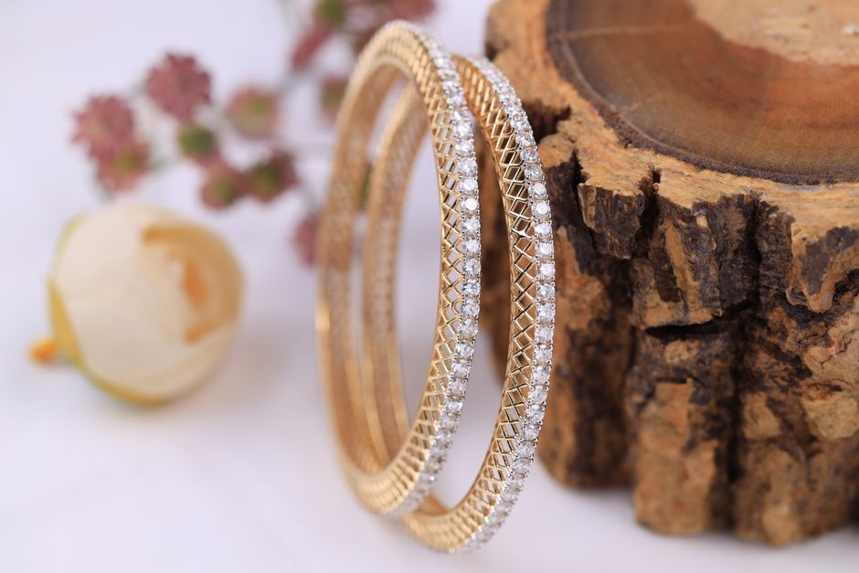 Close-up of luxurious gold bracelets with diamonds on a rustic wood slab, adding an elegant touch to any collection.