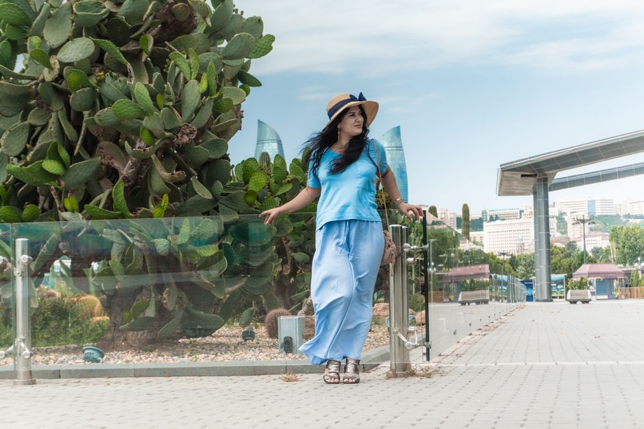 A woman in a summer hat enjoys a peaceful walk in Baku, Azerbaijan's scenic landscape.