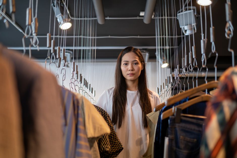 A young woman explores clothing options in a stylish, modern boutique.