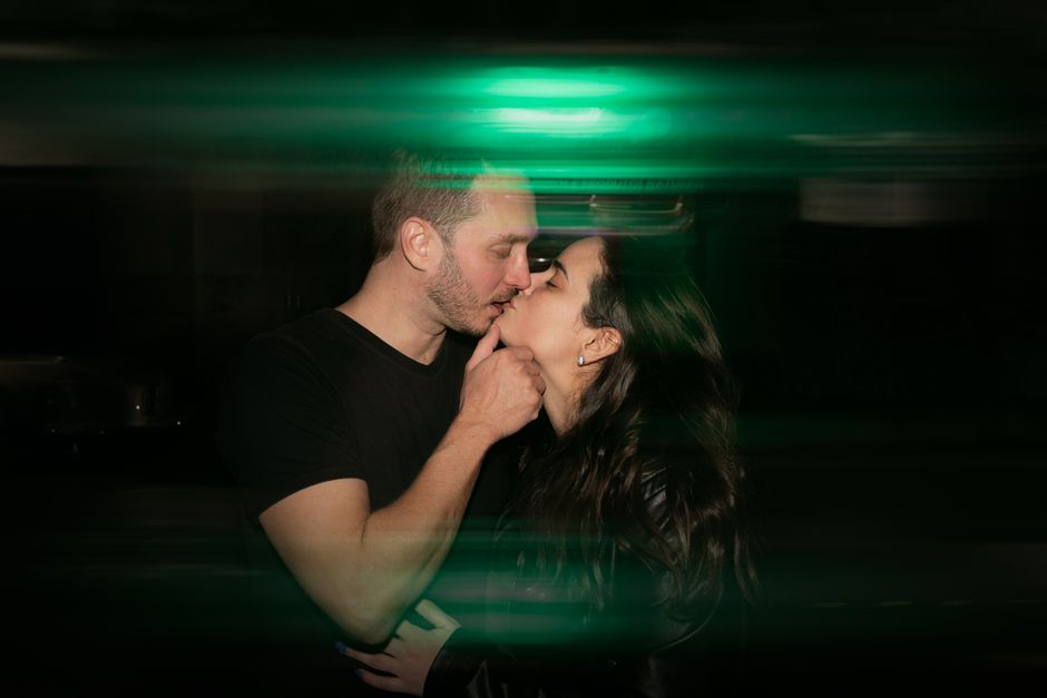 A couple shares a romantic kiss at night, captured with a dreamy effect.