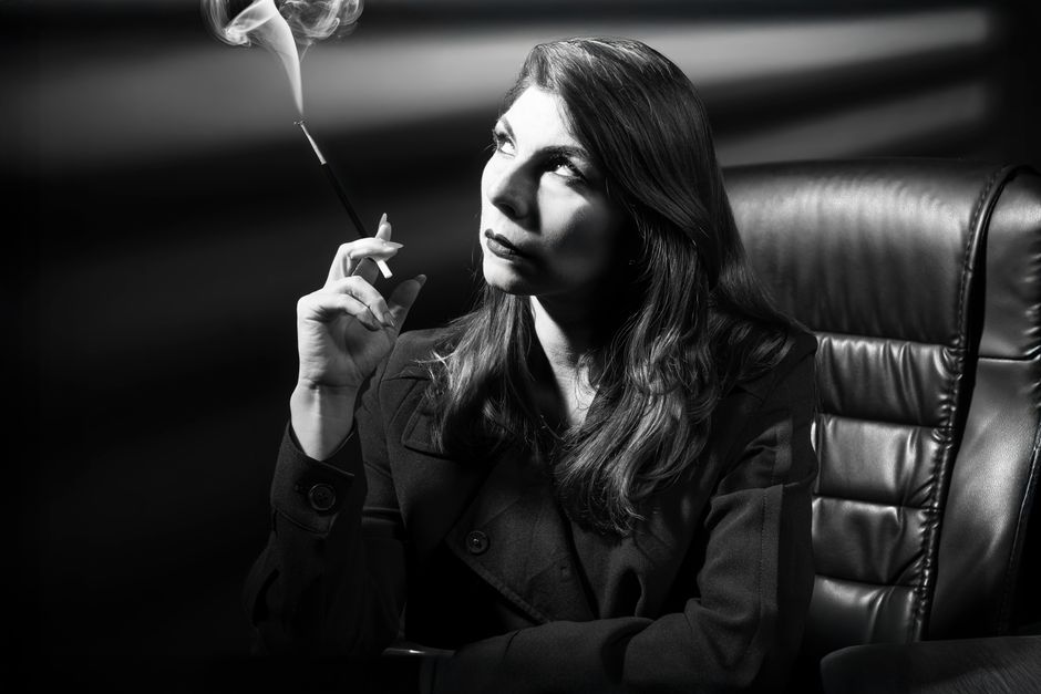 Sophisticated black and white portrait of a woman smoking, evoking film noir style.
