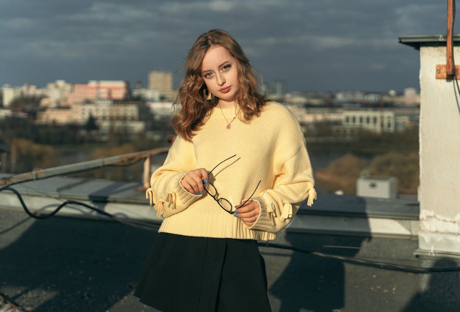 Stylish young woman in yellow sweater on a rooftop with cityscape view in Minsk, Belarus.