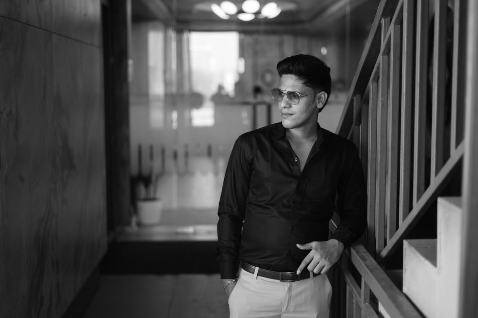 Elegant black and white portrait of a stylish man in a modern indoor environment.