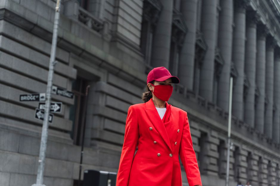 Stylish woman in red attire walking beside classic architecture.