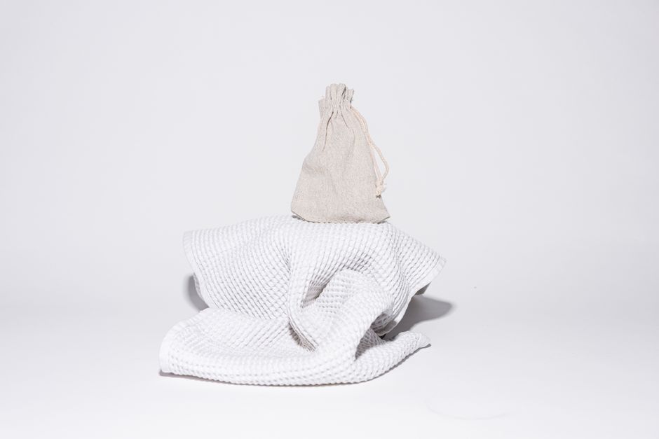 Elegant minimalist display of a sack on a towel against a white background, perfect for bathroom product presentations.