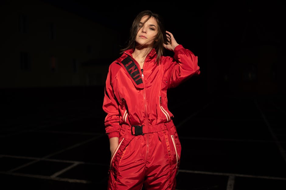 Stylish woman in a vibrant red jumpsuit posing confidently outdoors at night.